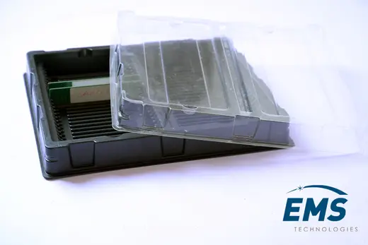 Black HIPS slotted ESD tray holding boards, with its clear PET lid lifted off, EMS Technologies