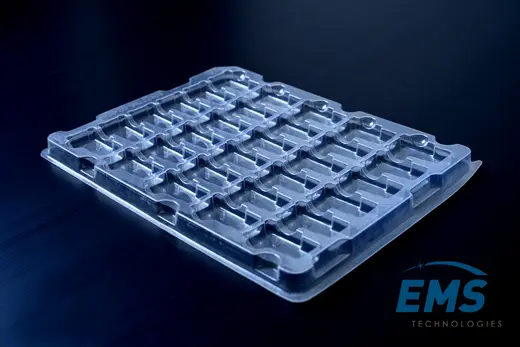 Clear anti-static PET tray marked ANTI STATIC, with a matrix of moulded component pockets, EMS Technologies