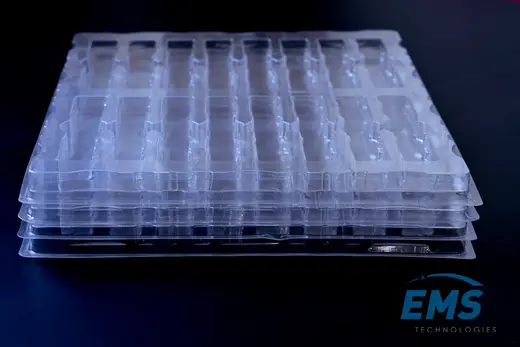 Nested stack of clear anti-static PET trays seen edge on, EMS Technologies