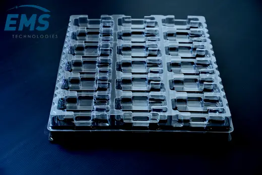 Clear anti-static PET tray with rows of moulded pockets on a black base tray, EMS Technologies