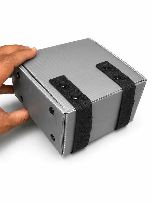 Grey PP corrugated ESD box closed with riveted webbing straps, held in one hand, EMS Technologies